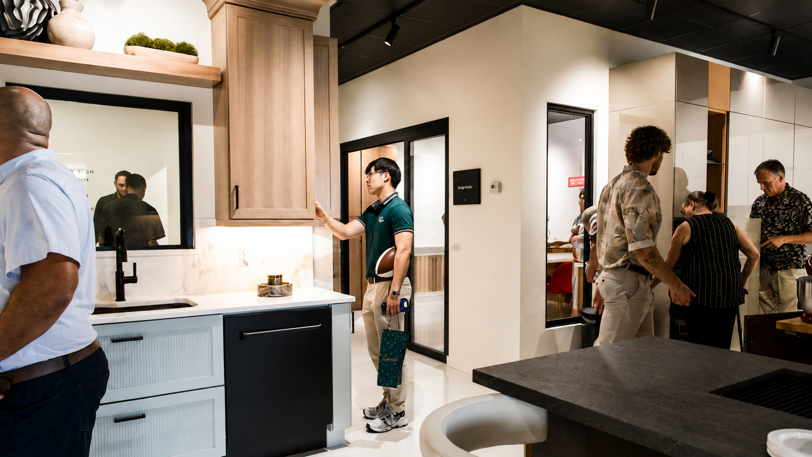 Wide view of guests exploring light wood cabinetry and dark countertops across the Cabinet IQ Tampa showroom floor