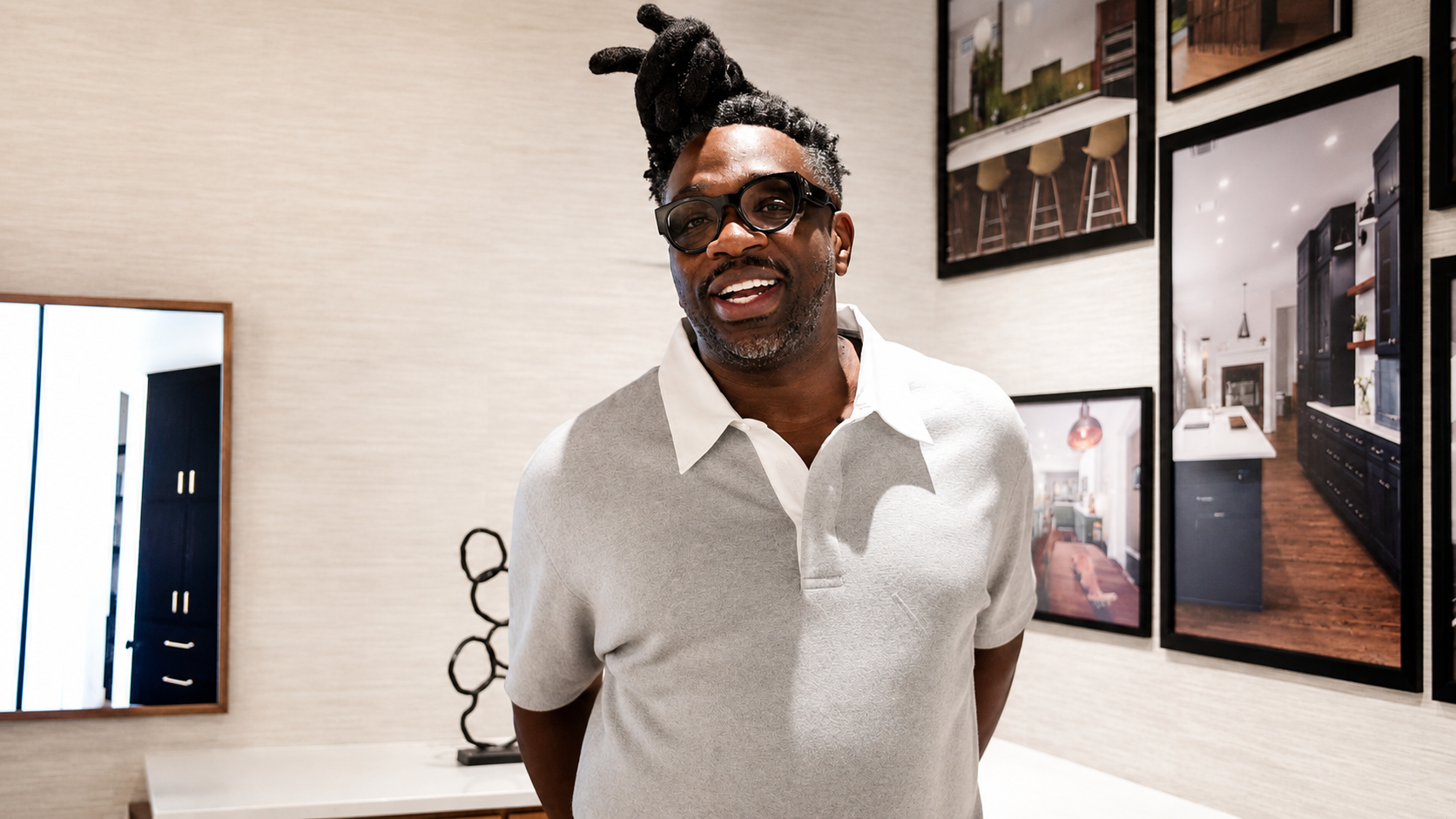Ameer Natson smiling inside the Cabinet IQ Tampa showroom, framed kitchen photography behind him