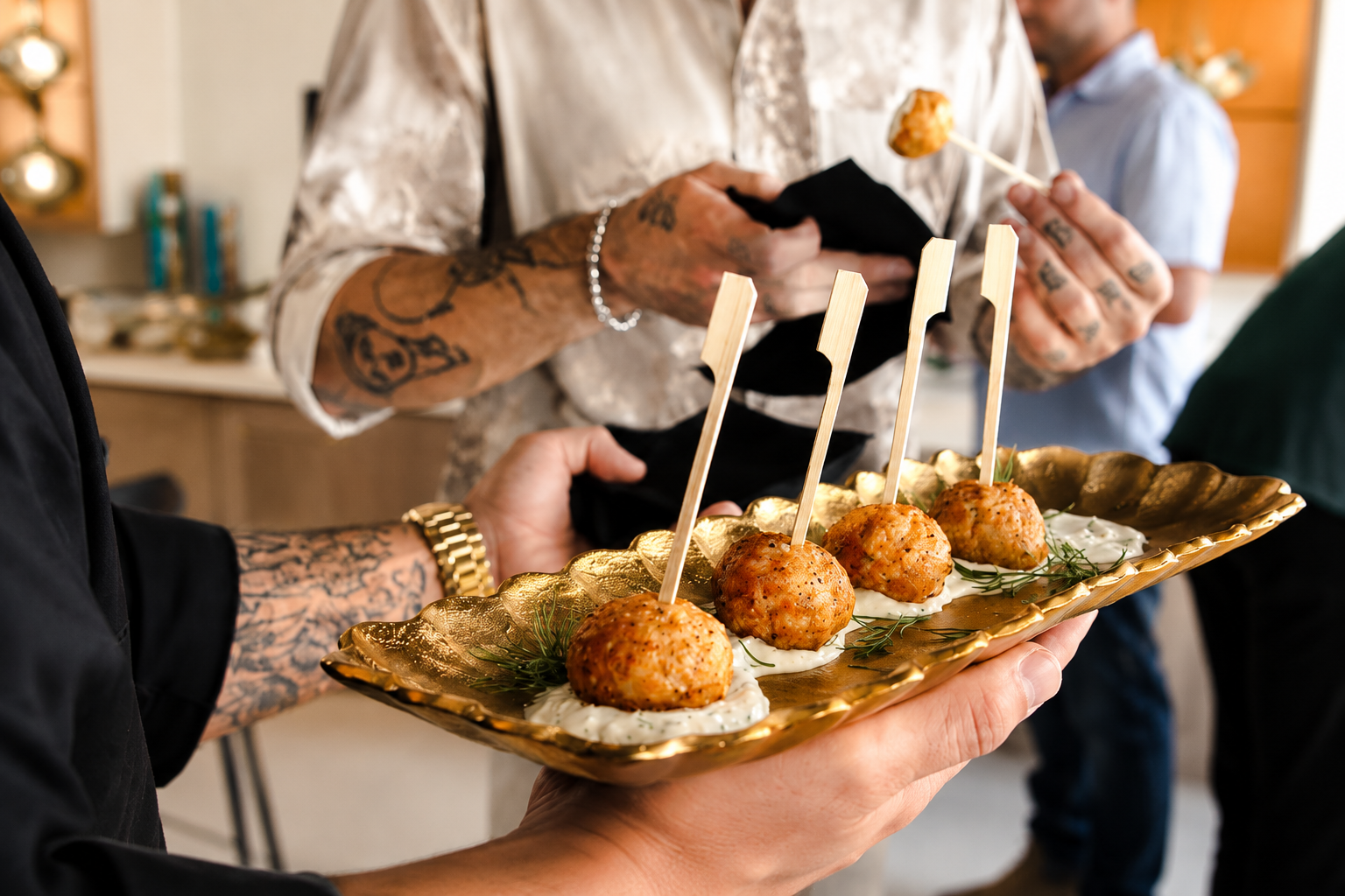 Close-up of four garnished appetizers passed on a gold serving tray during the Cabinet IQ Tampa opening